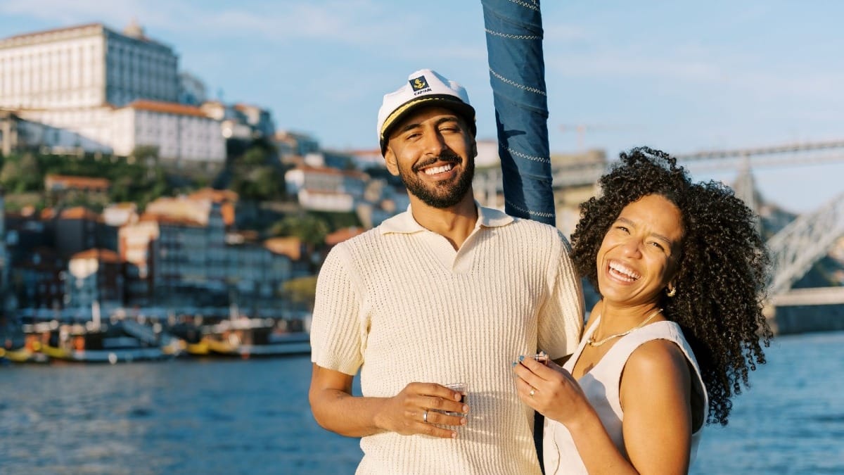 Happy couple enjoying the sun and scenic views from the bow of a boat on the Douro River in Porto