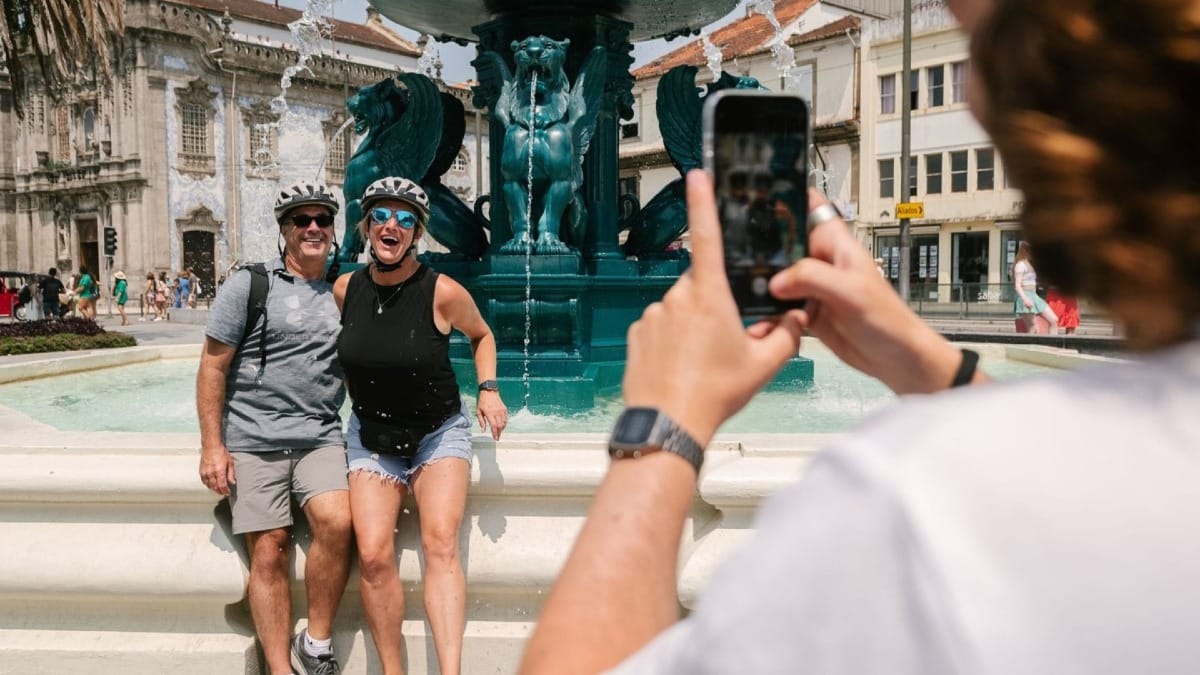 Tour guide capturing a photo of a happy couple by the Lions Fountain in Porto during an electric bike highlights and history tour