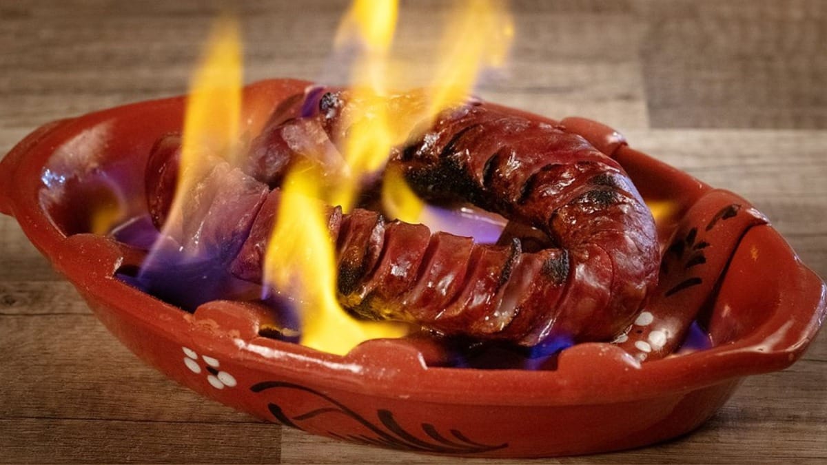 Flaming Portuguese chouriço served in a clay dish during an authentic Algarve food tasting
