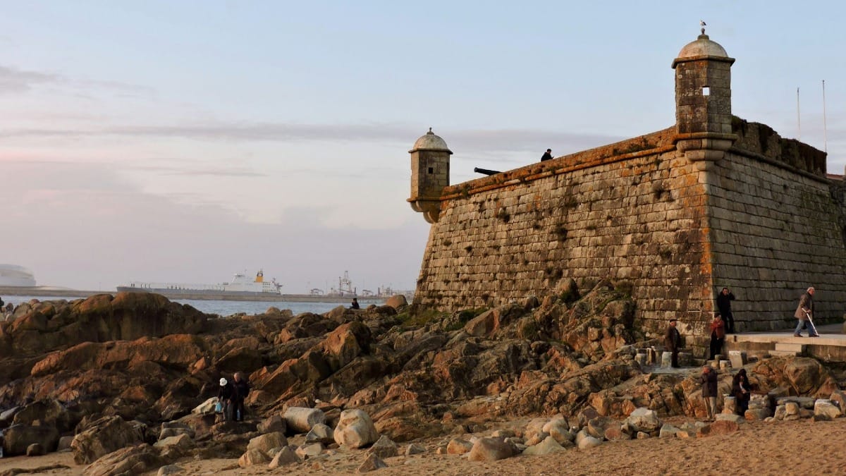Small group cycling past the historic Castelo do Queijo on Matosinhos Beach during an electric bike coastal and riverbank tour of Porto