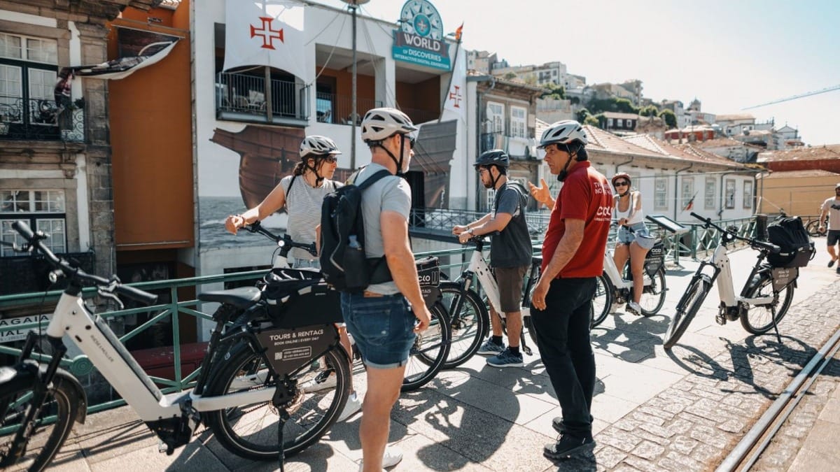 Guide sharing stories and fun facts with a small electric bike group in front of Porto’s Discoveries Museum