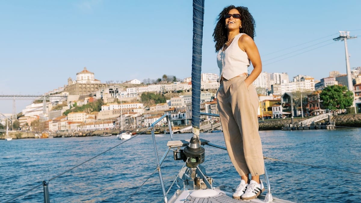 Guest relaxing on the bow during a Porto boat tour, with Gaia and the Port wine cellars in the background