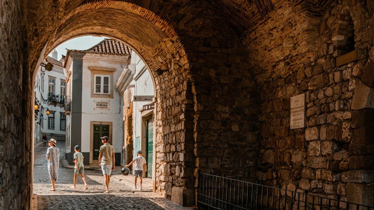 Family walking through a historic archway in Faro’s Old Town during a guided cultural tour