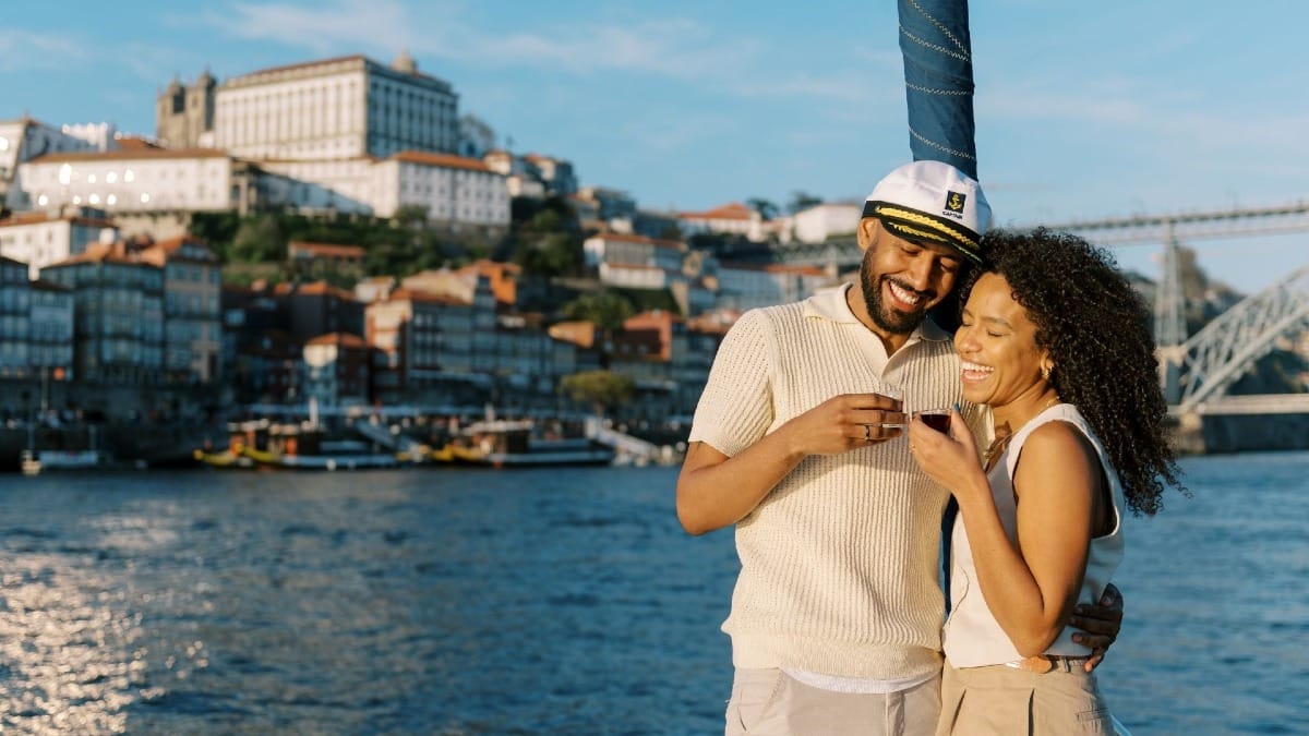 Couple toasting with a welcome drink on the bow during a daytime boat tour in Porto