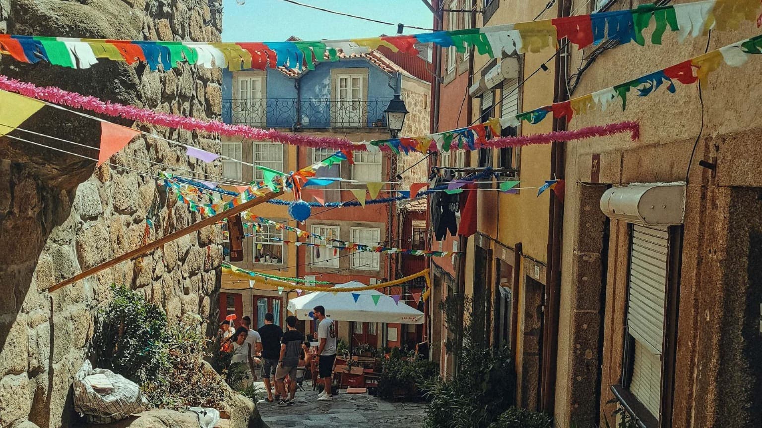 Colorful bunting and festival decorations hanging across a historic street in Porto during Festas de São João