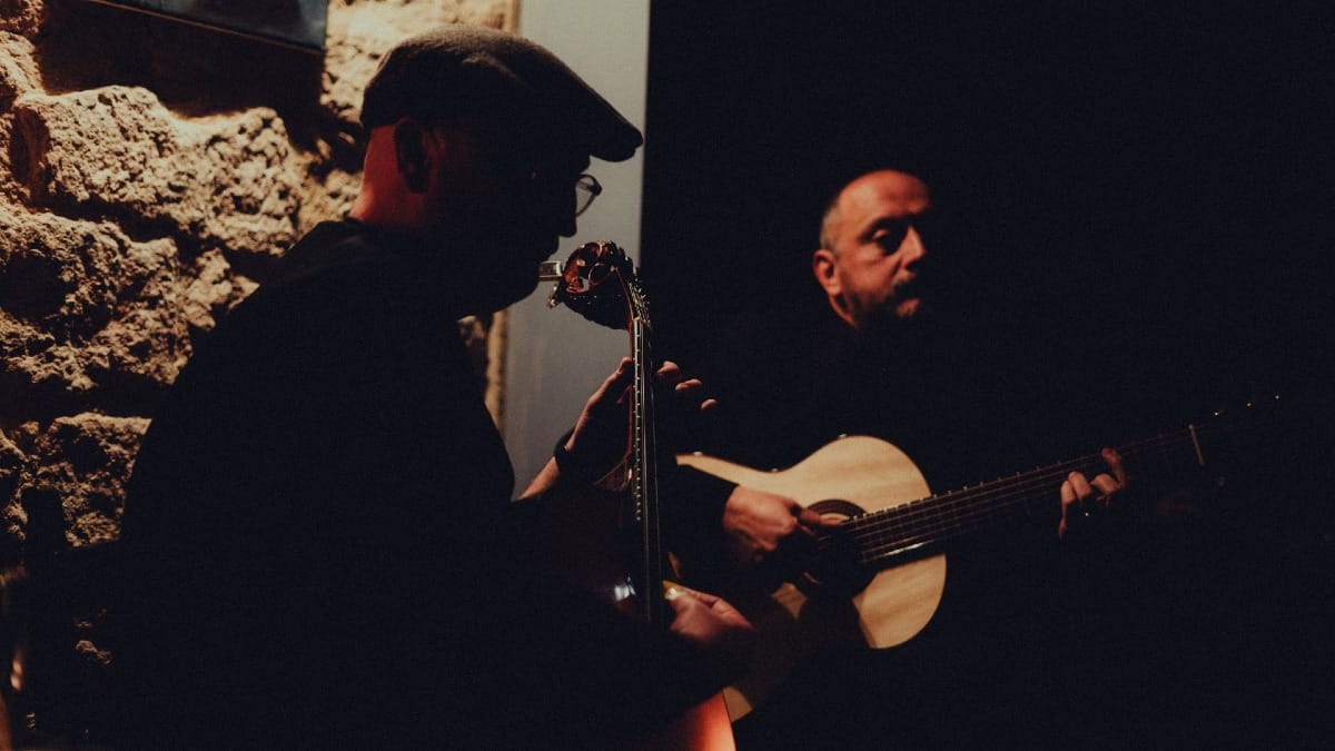 Dos músicos tocando en directo con una guitarra portuguesa y una guitarra clásica durante una cena-espectáculo de Fado en Oporto