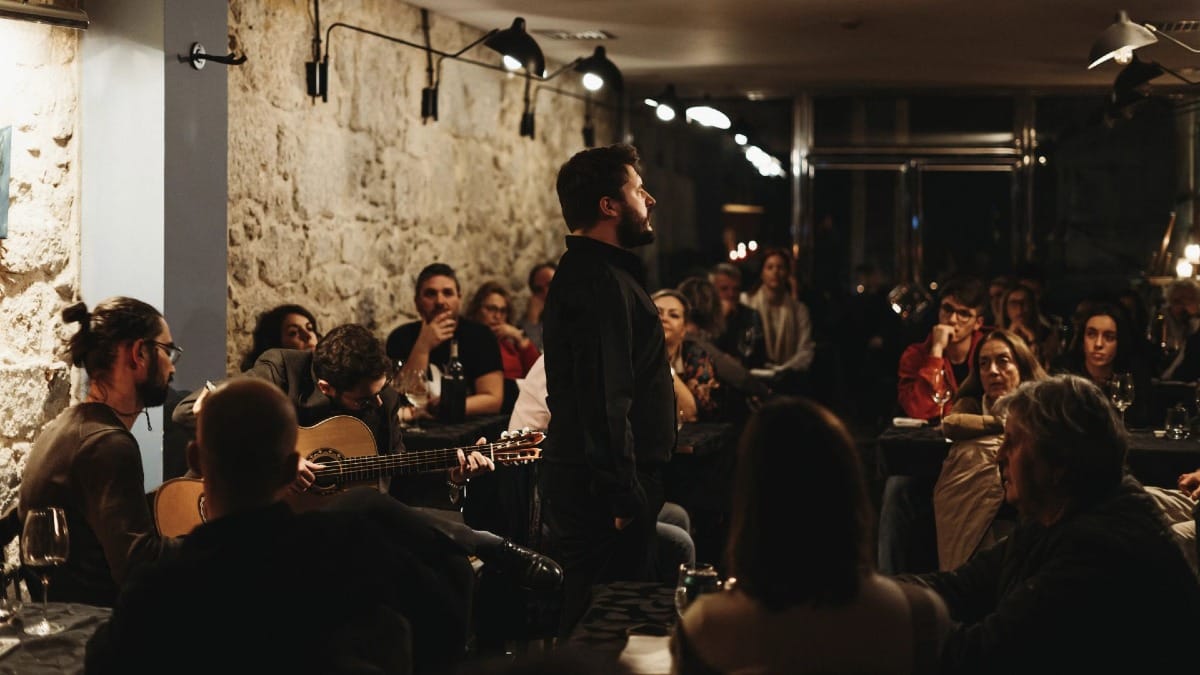 A male Fado singer performing in front of an attentive crowd at a local restaurant in Porto
