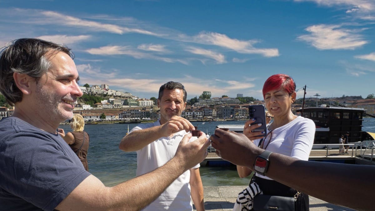 Invitados brindando con vino de Oporto junto al río durante una parada de cata con Cooltour Oporto