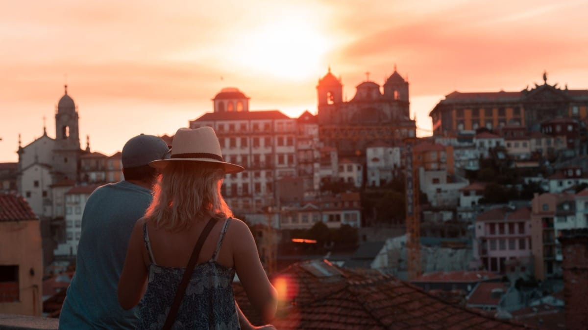 Pareja disfrutando del atardecer sobre el casco histórico de Oporto durante un tour de vinos y Fado