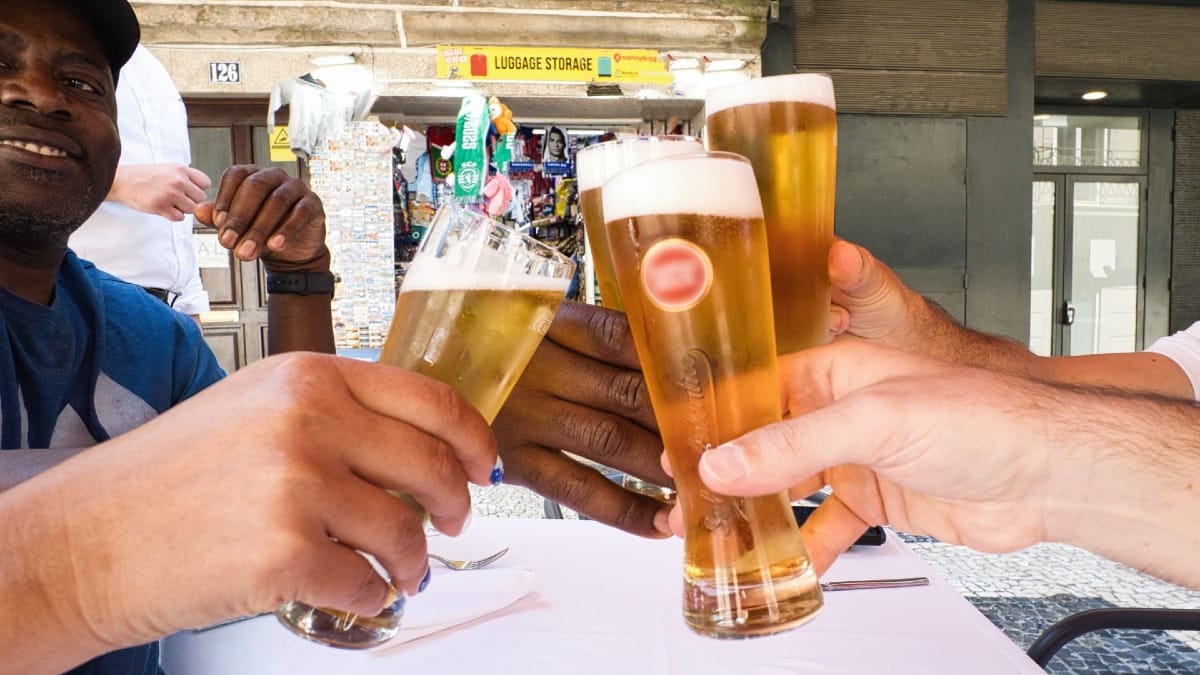 Invitados brindando con cerveza portuguesa de barril en la terraza de un restaurante durante el Food Tour de Cooltour Oporto