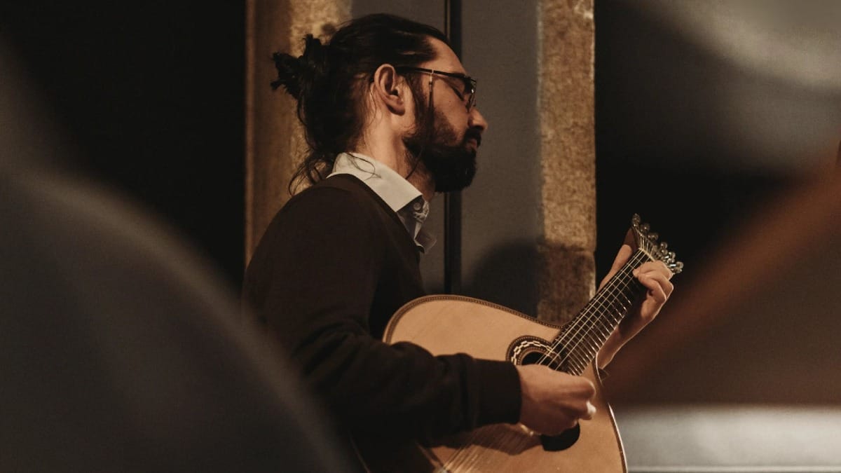 Guitarrista portugués tocando Fado en vivo en una sala con ambiente acogedor en Oporto