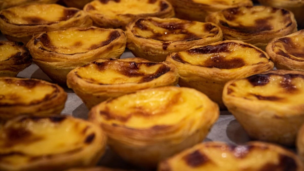 Pasteles de nata recién horneados con superficie caramelizada expuestos en una pastelería tradicional