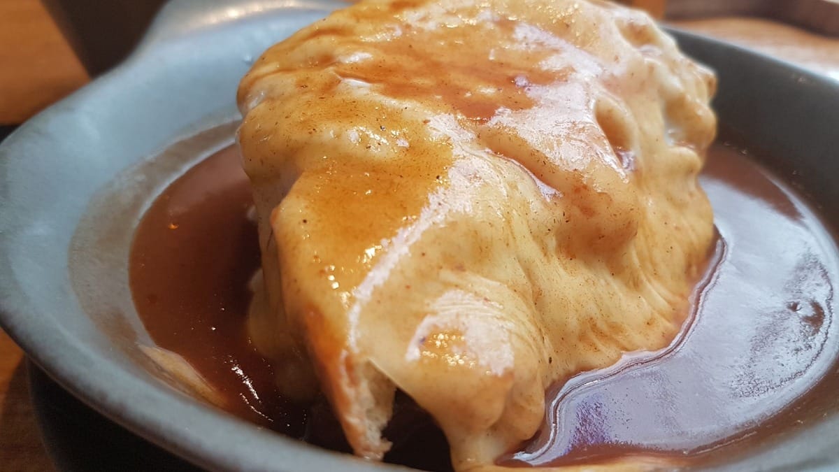 Primer plano de una Francesinha recién hecha cubierta con salsa picante, un manjar imprescindible en Oporto
