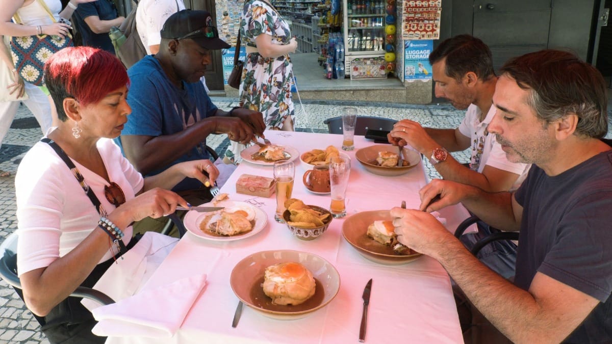 Invitados disfrutando de Francesinhas auténticas en un restaurante tradicional de Oporto, parte del Food Tour de Cooltour Oporto
