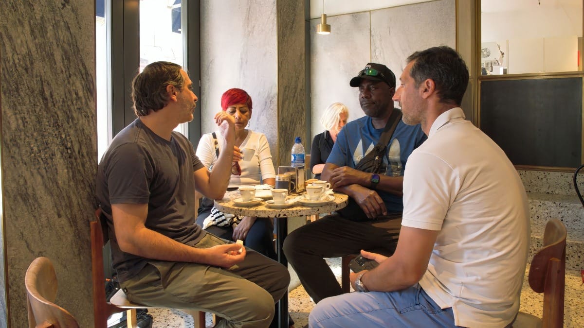 Viajeros disfrutando de café y pasteles de nata en una cafetería tradicional de Oporto durante una experiencia de Cooltour Oporto