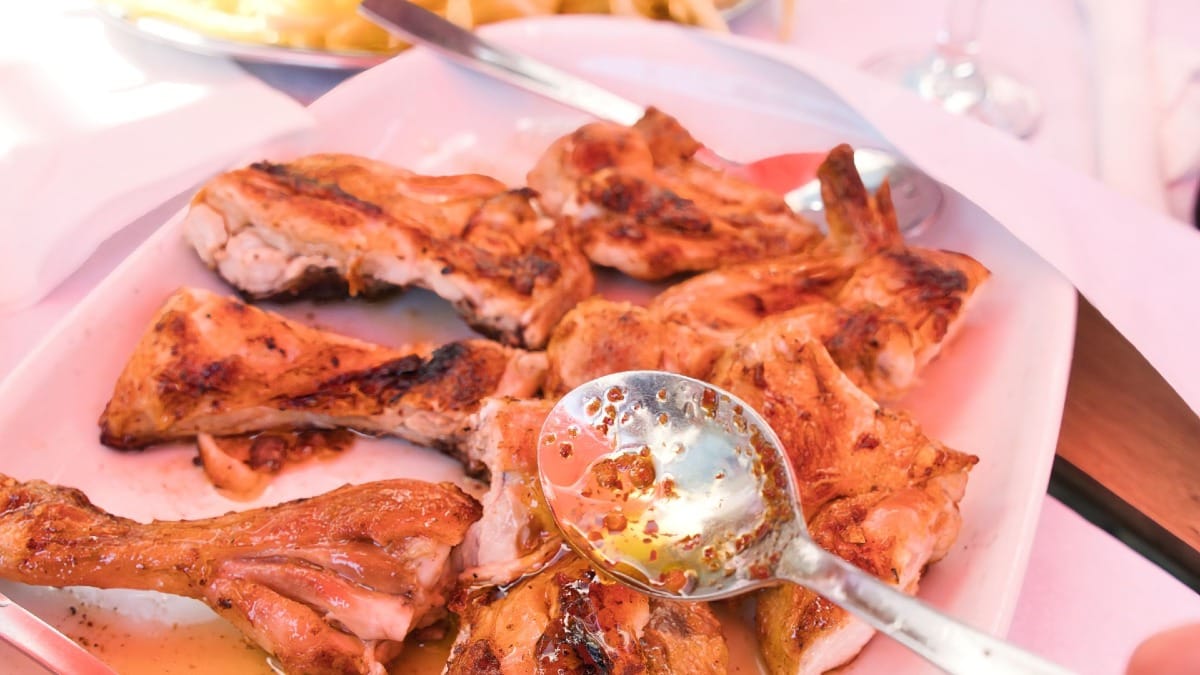 Frango piri-piri picante servido com óleo quente e pele crocante num restaurante local do Porto