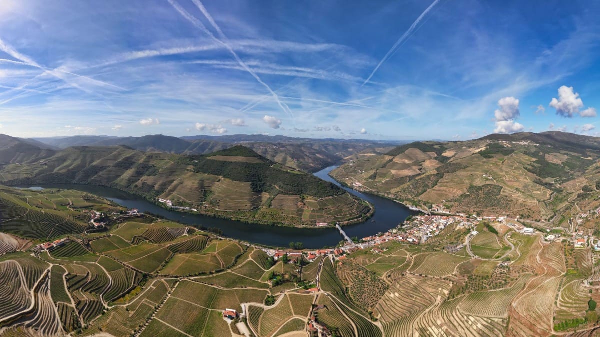 Miradouro em Pinhão com vista para o Rio Douro e vinhedos sob um céu azul durante um tour guiado pelo Vale do Douro com a Cooltour Oporto