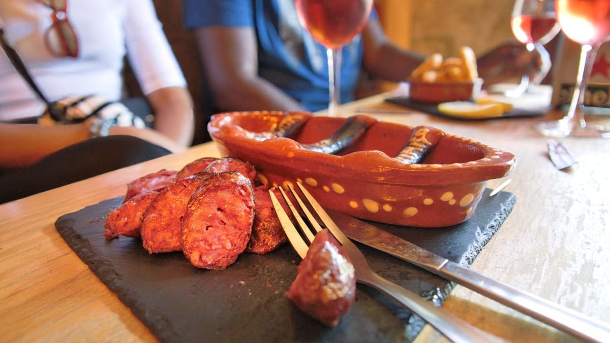 Primer plano de chorizo portugués a la parrilla recién cortado tras ser flameado en un plato de barro