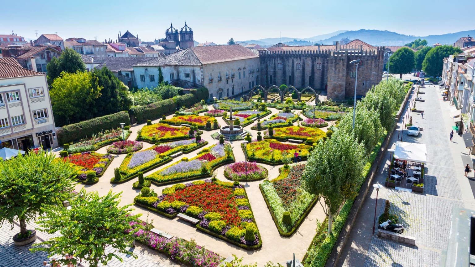 Santa Bárbara Garden in Braga city centre with colorful flowers and the medieval Archbishop’s Palace in northern Portugal