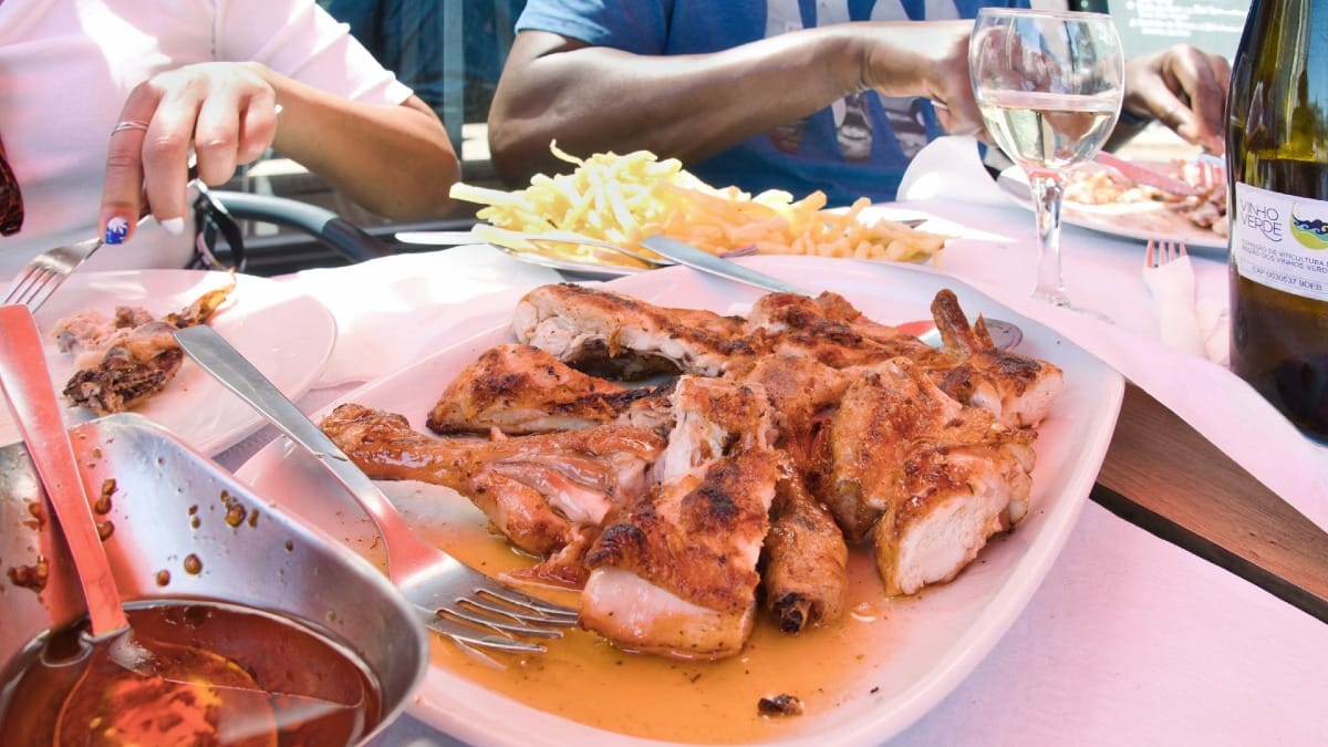 Pollo a la parrilla tradicional portugués con papas fritas y vino verde servido durante un food tour de Cooltour Oporto